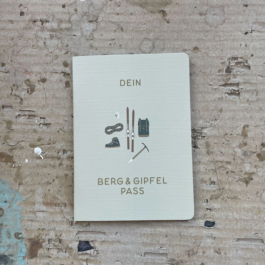 Roadtyping Berg- und Gipfelpass, offen auf einer Seite, mit vorgefertigten Feldern und Zeilen zum Eintragen von Wanderungen, Erlebnissen und Stempeln. Er ist für Abenteurer, Wanderer, Kletterer und Mountainbiker gedacht, aber auch für jeden, der seine Bergmomente festhalten möchte.